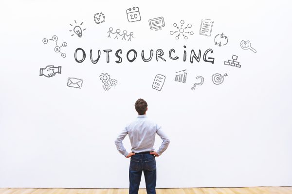 outsourcing concept - a man standing in front of some icons and an Outsourcing headline